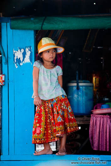 Small girl standing in a window frame near Tonle Sap lake