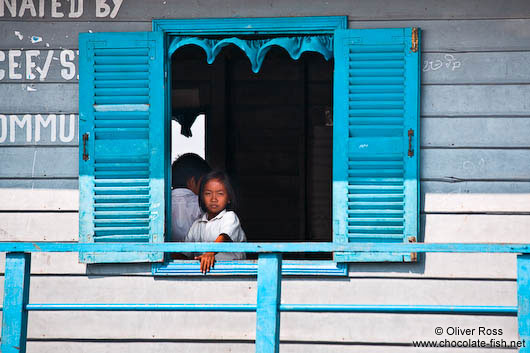 Girl looking out from her school`s window near Tonle Sap lake