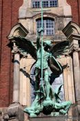 Travel photography:Bronze sculpture of the archangel Michael defeating the devil above the entrance portal of St. Michaelis church (Michel), Germany