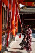Travel photography:Two girls in Kimono pray at  Kyoto´s Inari shrine, Japan