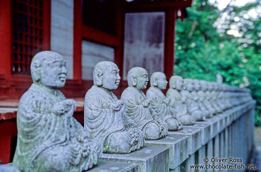 Row of little buddhas outside a forest shrine
