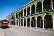 Travel photography:Colonnades along the main square in Campeche with tourist bus, Mexico
