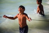 Travel photography:Boy in Celestun asking the arriving fishermen for some fish, Mexico