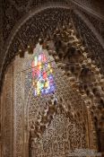 Travel photography:Sunlight enters through a coloured window into an ornate arabesque alcove of the Nazrin palace in the ranada Alhambra, Spain