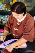 Travel photography:Woman painting a fan at the Bo Sang parasol factory, Thailand