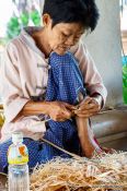 Travel photography:Woman cutting small pieces of wood at the Bo Sang parasol factory, Thailand